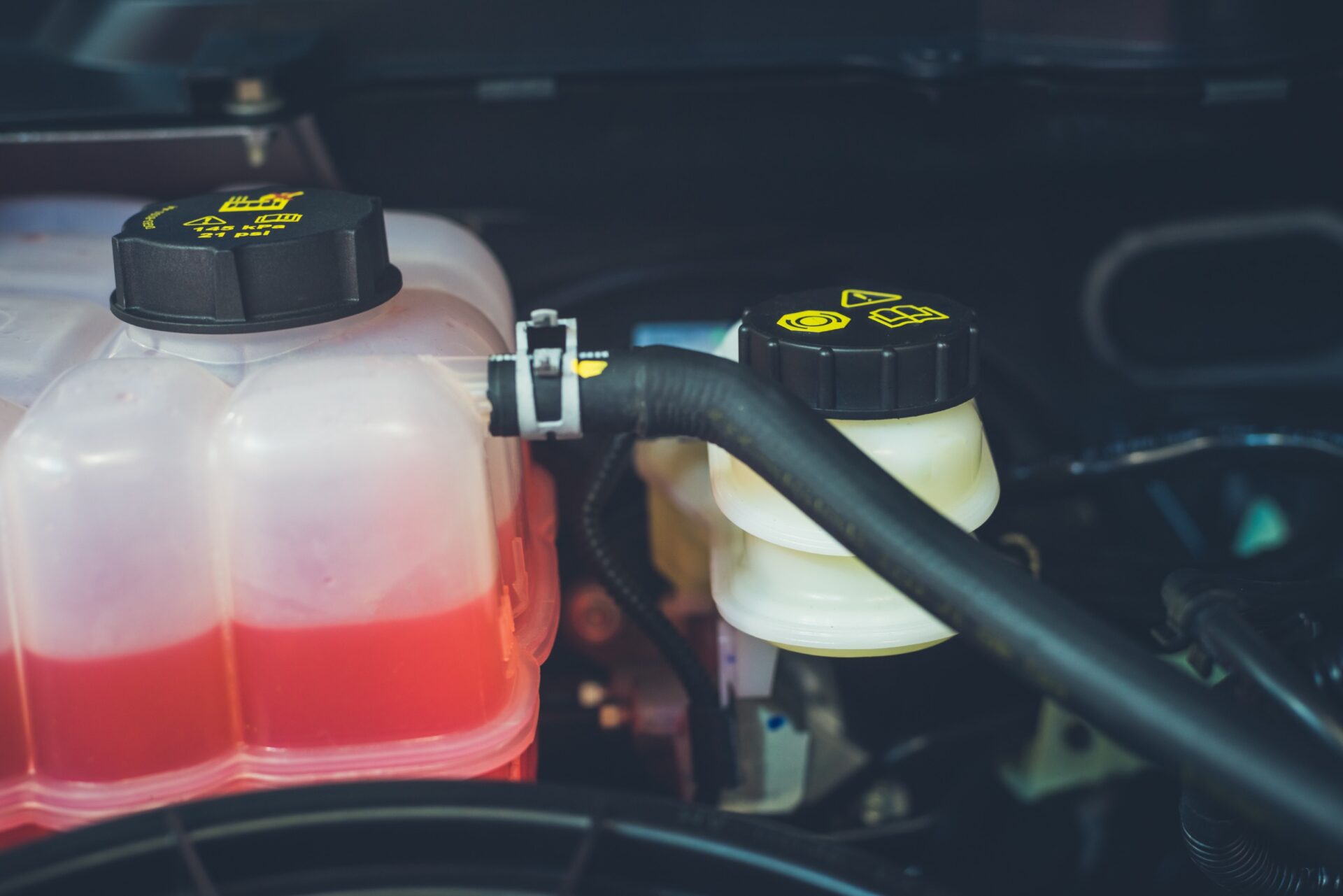 close up on car engine bay with coolant reservoir 